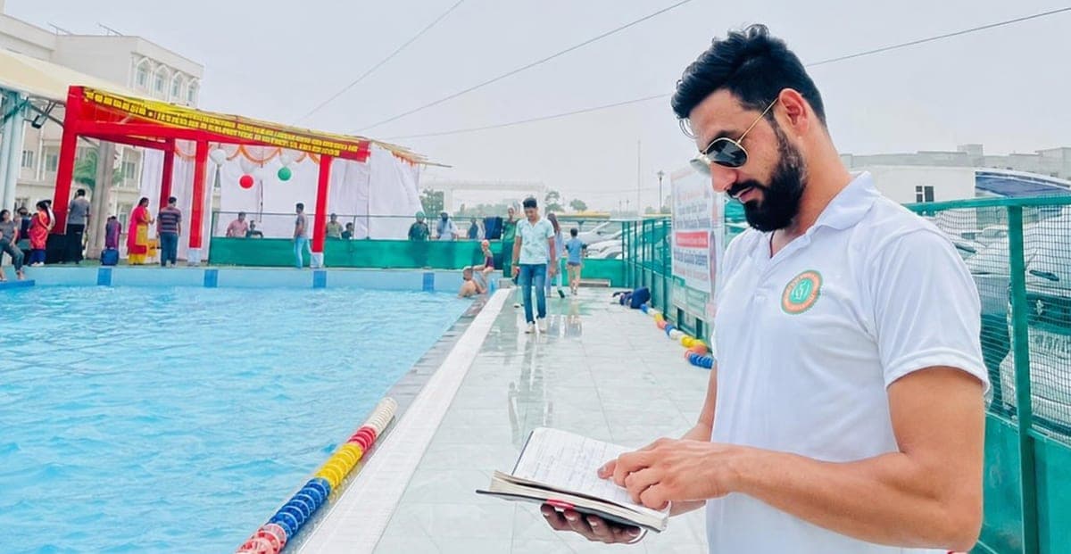 Coach checking the batch register poolside at The Breathe Swimming Academy, Gurgaon
